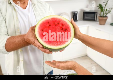 Reifes Paar mit der Hälfte Wassermelone in der Küche, Nahaufnahme Stockfoto