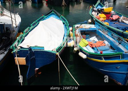 Farbenfrohe Holzfischboote liegen am Ufer. Einige der Boote sind mit Gegenständen ausgestattet, die zum Angeln benötigt werden. Dies sind traditionelle Boote auf Malta. Stockfoto