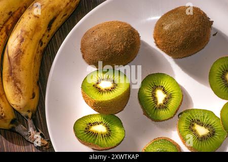 Kiwi und Kiwi schneiden auf einer weißen Platte Stockfoto