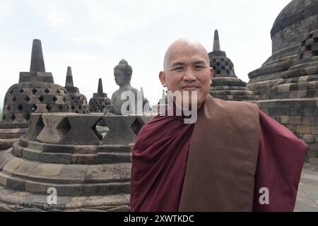 Ein buddhistischer Mönch besucht die Tempelanlage Borobudur. Im Hintergrund sind Buddhafiguren und stupas zu sehen. In Borobudur türmen sich neun Stockwerke auf der quadratischen Basis von 123 Metern Länge auf. An den Wänden der vier sich stufenartig verjüngenden Galerien befinden sich Flachreliefs in der Gesamtlänge von über fünf Kilometern, welches das Leben und Wirken Buddhas beschrieben. Darüber liegen drei sich konzentrisch verjüngende Terrassen mit insgesamt 76 Stupas, welche den Hauptstupa von fast 11 Meter Durchmesser umrahmen. Borobudur ist die größte buddhistische Tempelanlage der wel Stockfoto