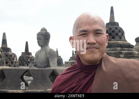 Ein buddhistischer Mönch besucht die Tempelanlage Borobudur. Im Hintergrund sind Buddhafiguren und stupas zu sehen. In Borobudur türmen sich neun Stockwerke auf der quadratischen Basis von 123 Metern Länge auf. An den Wänden der vier sich stufenartig verjüngenden Galerien befinden sich Flachreliefs in der Gesamtlänge von über fünf Kilometern, welches das Leben und Wirken Buddhas beschrieben. Darüber liegen drei sich konzentrisch verjüngende Terrassen mit insgesamt 76 Stupas, welche den Hauptstupa von fast 11 Meter Durchmesser umrahmen. Borobudur ist die größte buddhistische Tempelanlage der wel Stockfoto