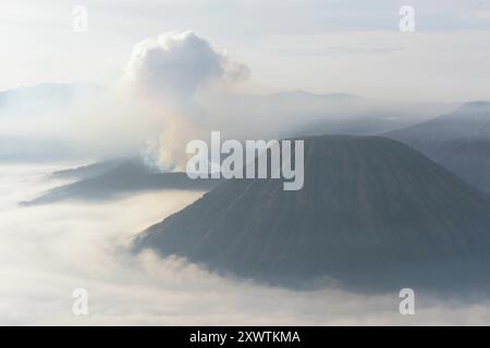 Links ist der Bromo rauchender Krater / Höhe: 2,329 Meter und rechts der Batok zu sehen. Der Nationalpark Bromo-Tengger-Semeru besteht seit 1982. Der mittlere Teil des Namens verweist auf das hier lebende Volk der Tengger. Zum Nationalpark gehören der 3676 m hohe Stratovulkan Semeru, der höchste Berg der Insel, sowie vier in der Tengger-Caldera liegende Vulkane, deren Bekanntester der Bromo ist. Die Caldera wird vom Tengger-Sandmeer malaiisch: Laut Pasir Tengger ausgefüllt. Vier gesehen und etwa 50 Flüsse liegen auf dem Gelände. Bereits seit 1919 steht das Sandmeer unter besonderem Schutz. *** Ein Stockfoto