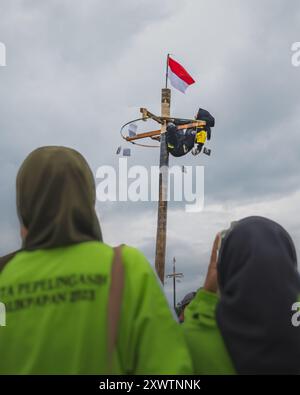 Balikpapan, Indonesien - 18. August 2024. Die beiden Zuschauerinnen beobachten und fotografieren die Klettererin im Panjat Pinang Wettbewerb Stockfoto