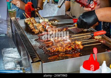 Schweinekebabs auf Holzspießen, die an einem Marktstand in Tanjung Bunghah, Penang, Malaysia, gekocht werden Stockfoto