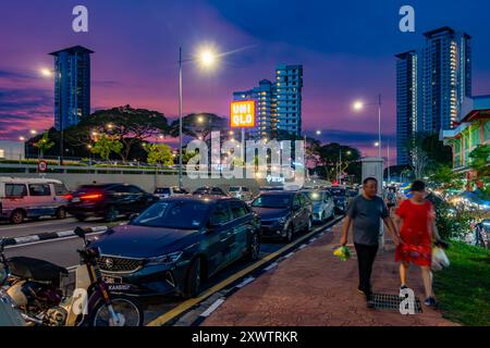 Eine Straße, Jalan Sungai Kelian, in Tanjung Bungha, Penang, Malaysai, ist Dienstagabend mit geparkten Autos beschäftigt. Das ist ein farbenfroher Sonnenuntergang. Stockfoto