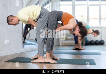 Acroyoga, zwei sportliche Menschen üben Yoga in Paaren, Paare, die Dehnübungen machen, Stehhaltung halber Vorwärtsbeugung im Yoga-Club Stockfoto