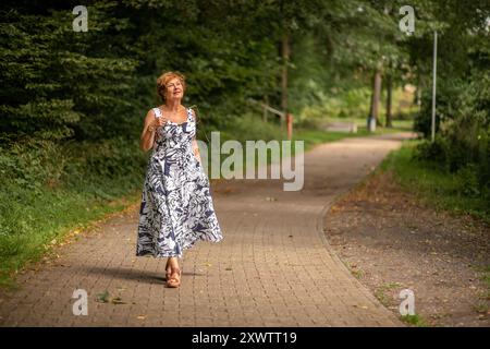 Eine Frau genießt einen gemütlichen Spaziergang entlang eines ruhigen Weges umgeben von lebhaftem Grün. Stockfoto