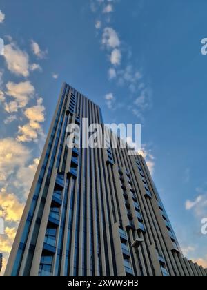 Tiefwinkelblick auf einen modernen Hochhaus-Wolkenkratzer vor einem Himmel mit Wolken Stockfoto