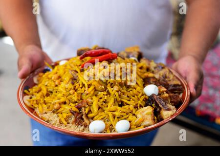 Plov ist das Nationalgericht Usbekistans. Ein usbekischer Mann mit einem Teller traditioneller Plov in einem kleinen Restaurant in Samarkand, Usbekistan. Stockfoto
