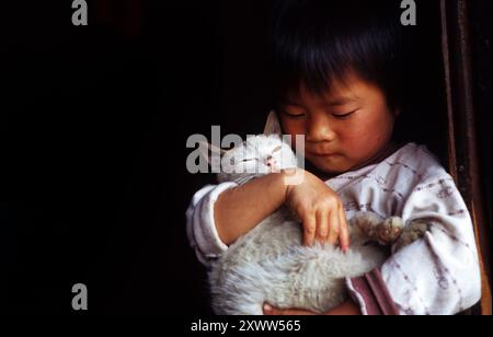 Ein kleines Mädchen aus der Miao-Minderheit hält ihre süße Katze. Foto in Guizhou, China. Stockfoto