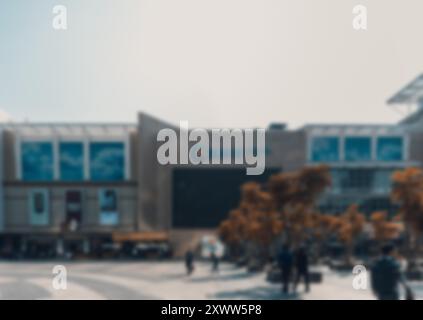 Ein verschwommener Blick auf eine Straßenszene in Shenzhen, China. Die Menschen gehen an modernen Gebäuden und Bäumen vorbei und schaffen einen Bokeh-Hintergrund. Stockfoto