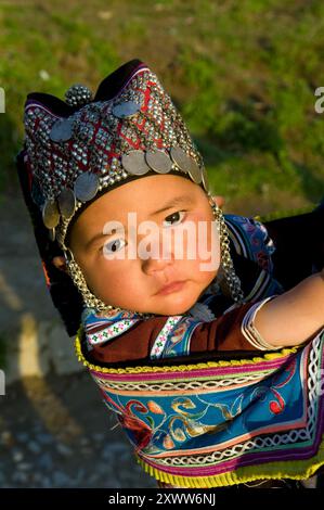 Ein süßes Hani-Baby mit traditionellem Hut. Yuanyang County, Yunnan, China. Stockfoto