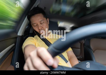 Fahrer schläft ein, verschwommener Vordergrund. Ein müder Mann gähnt, während er sein Auto fährt. Müder Fahrer schläft beim Autofahren ein. Verschlafener Mann, der se trägt Stockfoto