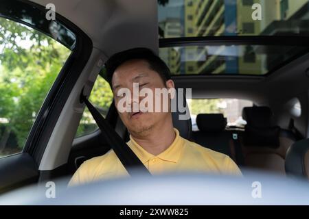 Mann, der im Auto schläft. Müder junger Mann, der sein Auto fährt, der Mann schläft im Auto, während er auf der Straße fährt. Stockfoto