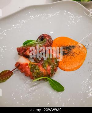 Gegrillte Kraken-Tentakel mit Orangensauce und Rucola, Blick von oben, vertikal, Restaurant-Gericht Stockfoto