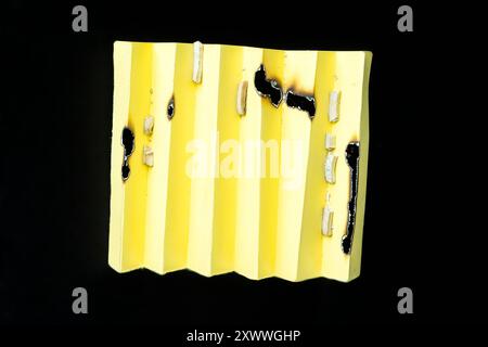 Ein gelbes Stück Papier mit schwarzen Brandspuren drauf Stockfoto