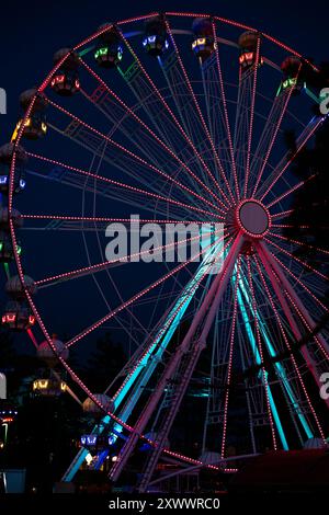 Ein farbenfrohes Riesenrad im Luna Park während der Nacht. Vertikales Foto des Riesenrads mit langer Belichtung. Stockfoto