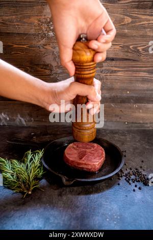 Eine Person mahlt Filet mit einer Pfeffermühle Stockfoto