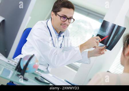 Arzt erklärt dem Patienten in der Praxis die Wirbelsäulenröntgenaufnahme Stockfoto