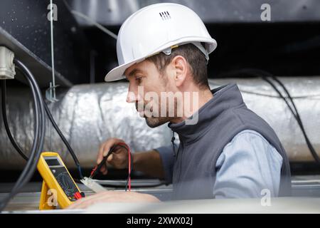 Elektriker die Messung der Spannung der Kabel an der Decke im Innenbereich Stockfoto