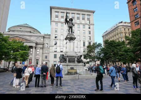 Kanada, Québec, Montreal: Eine Gruppe von Touristen, die das Denkmal für Paul de Chomedey, sieur de Maisonneuve, auf dem Platz „Place d'Armes“ vor dem Hotel bewundern Stockfoto