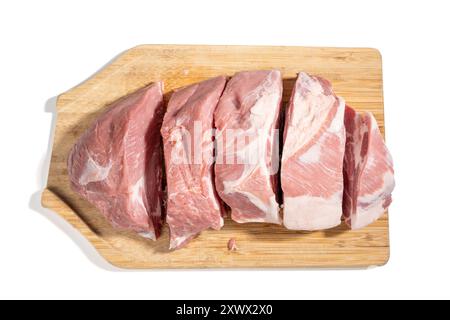 Ein Stück Fleisch wird in Stücke geschnitten und auf einem hölzernen Schneidebrett auf weißem Hintergrund verteilt. Vorkochkonzept: Fleisch wird geschnitten und platziert Stockfoto