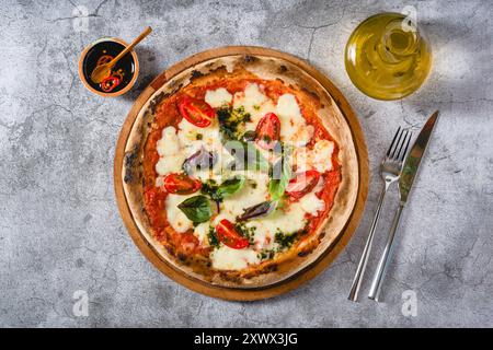 Neapolitanische Margherita-Pizza mit Tomaten, Mozzarella, Basilikum und Oliven auf Steintisch Stockfoto