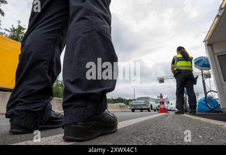 Walserberg, Österreich. August 2024. Polizeibeamte stehen bei Grenzkontrollen durch die Bundespolizei am Grenzübergang zwischen Österreich und Deutschland an der Autobahn A8 bei Salzburg (Österreich). Hinweis: Peter Kneffel/dpa – ACHTUNG: Nummernschildnummern wurden aus rechtlichen Gründen pixeliert/dpa/Alamy Live News Stockfoto