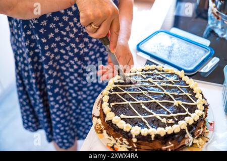Der Prozess des Nahaufschneidens eines selbstgemachten Schokoladenkuchens von Oma. Konzept von Familienurlaub und Tradition mit Backen. Stockfoto