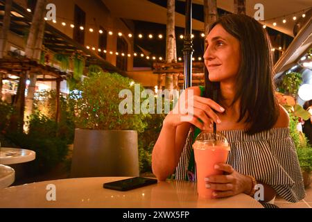 Nahaufnahme junge hübsche kaukasische Frau sitzen drinnen im asiatischen Café trinken Sie gesunden rosa thai Smoothie in südostasien, Bangkok, Thailand. Asiatique Popu Stockfoto