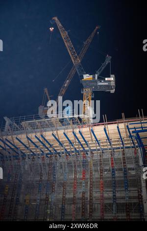 Nächtlicher Blick auf die Baustelle des Amazonasturms in Berlin mit Kränen und weitläufigen Gerüsten. Dieses Bild symbolisiert Fortschritt, Entwicklung und den Ehrgeiz des städtischen Wachstums. Stockfoto