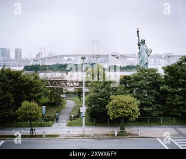 Bild der Nachbildung der Freiheitsstatue in Odaiba, Tokio, Japan, mit der berühmten Regenbogenbrücke im Hintergrund. Aufgenommen im Juli 2008, zeigt die einzigartige urbane Landschaft. Stockfoto