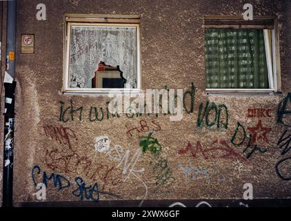 Graffiti auf einer Stadtmauer in Berlin, 2005, mit der deutschen Botschaft "Ich will ein Kind von dir". Zwei Fenster mit verschiedenen Vorhängen sind über dem Graffiti zu sehen. Stockfoto