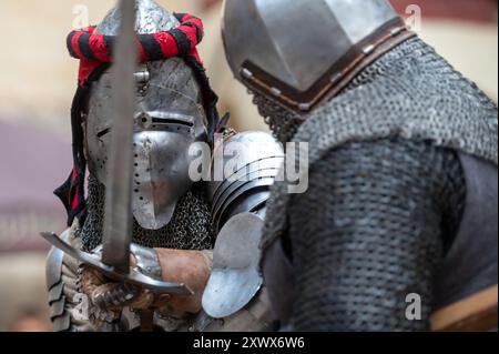 Jaunpils, Lettland – 10. August 2024: Zwei gepanzerte Ritter kämpfen mit Schwertern bei einer Nachstellung. Stockfoto