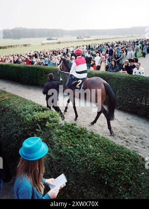 Jockey Andreas Suborics auf dem Pferderücken mit ÜBERDOSIERUNG bereitet sich auf ein aufregendes Rennen beim Saisonauftakt 2011 auf der Berliner Hoppegarten-Strecke vor. Die Zuschauer beobachten gespannt, wie sich die Spannung für das bevorstehende Rennen entwickelt. Stockfoto