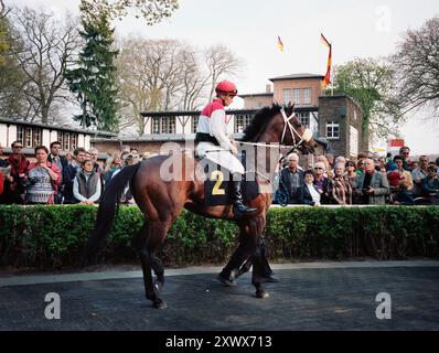 Jockey Andreas Suborics und Rennpferd-ÜBERDOSIERUNG im Fahrerlager auf der Hoppegarten-Rennstrecke in Berlin während des Saisonauftakts am 17. April 2011. Die Szene fängt die Vorfreude und Energie eines Pferderennens ein, bei dem die Zuschauer eifrig zusehen. Stockfoto