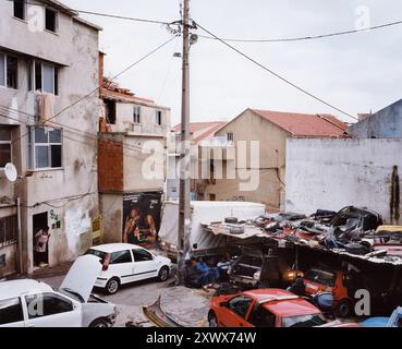 Autowerkstatt im Stadtteil Couva da Moura, Lissabon, Portugal. Die Rahmenbedingungen spiegeln die Herausforderungen wider, denen sich die Gemeinschaft gegenübersieht, einschließlich wirtschaftlicher Schwierigkeiten und der Abhängigkeit von informellen Industrien. 2006 Stockfoto