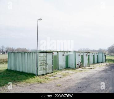 Eine Reihe grüner provisorischer Unterkünfte auf dem Land Hamburgs, die als temporärer Wohnraum für Obdachlose dienen und Widerstandskraft und die Suche nach Stabilität unter unsicheren Bedingungen symbolisieren. Stockfoto