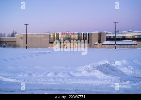 Ein leerer, schneebedeckter Parkplatz der Northway Mall in Anchorage, Alaska, zeigt die Stille und Kälte des Winters in der Nähe des Merrill Field Airport in Anchorage, Alaska. Die Szene weckt Gefühle von Einsamkeit und ruhiger Schönheit. Stockfoto