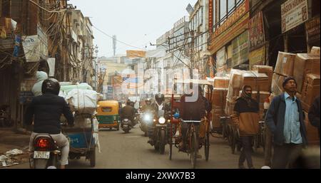 Neu-Delhi, Delhi, Indien. Verkehr auf dem Kucha Pati RAM, Chandni Chowk Street. Autos, Motorräder, Rikscha oder Tuk-Tuk, die sich am nebeligen Morgen auf der Straße bewegen Stockfoto