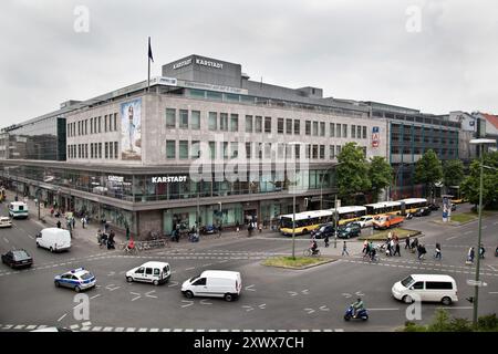Eine geschäftige urbane Szene vor dem Kaufhaus Karstadt am Hermannplatz in Berlin-Neukölln, 2010 aufgenommen. Das Bild zeigt geschäftige Fußgänger, Autos und Busse und spiegelt das pulsierende Stadtleben und die berühmte Architektur wider. Stockfoto