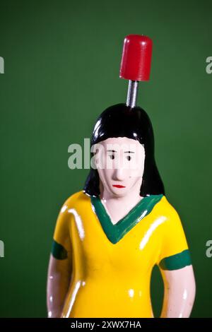 Nahaufnahme der ersten weiblichen Tipp-Kick-Figur mit gelbem Jersey und schwarzem Haar auf grünem Hintergrund. Ein Symbol für Inklusion und Vielfalt bei Tischfußballspielen. Stockfoto