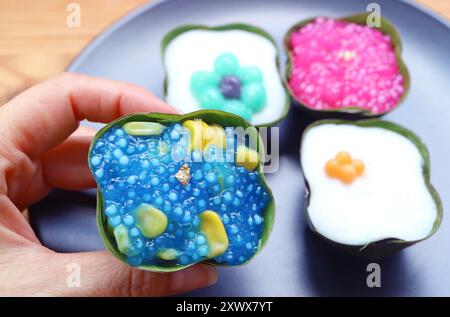 Handpflückendes thailändisches Dessert aus zweischichtigem Kokosnussmilchpudding namens Khanom Tako in umgekehrter Version mit traditionellen Versionen in einem Teller Stockfoto