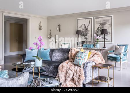 Orchid- und Pelzsofa mit Überwurf im Wohnzimmer des stilvollen, modernen Londoner Apartments, Großbritannien Stockfoto