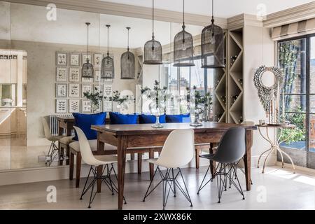 Elektrische blaue Polster auf der Bank am Tisch reflektieren Esszimmer im stilvollen, modernen Londoner Apartment, Großbritannien Stockfoto