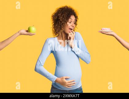 Afro schwangere Frau, die zwischen süß und Obst wählt Stockfoto