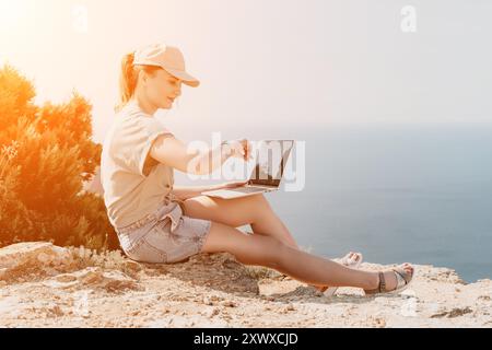 Frau, die an Laptop am Meer arbeitet Stockfoto