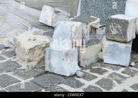 Graue Steine zur Reparatur. Der Straßenbelag wird auf der Straße gelegt. Straßenreparatur in der Stadt. Neuer Bürgersteig. Stockfoto