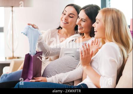 Geschenke für die junge Mutter. Glückliche junge schwangere Frau, die Geschenke von ihren Freunden auf der Babyparty erhält Stockfoto