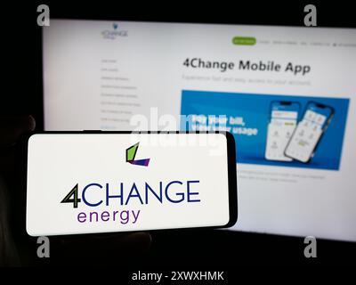 Person mit Smartphone und Logo des US-Stromunternehmens 4Change Energy vor der Website. Schwerpunkt auf dem Display des Telefons. Stockfoto